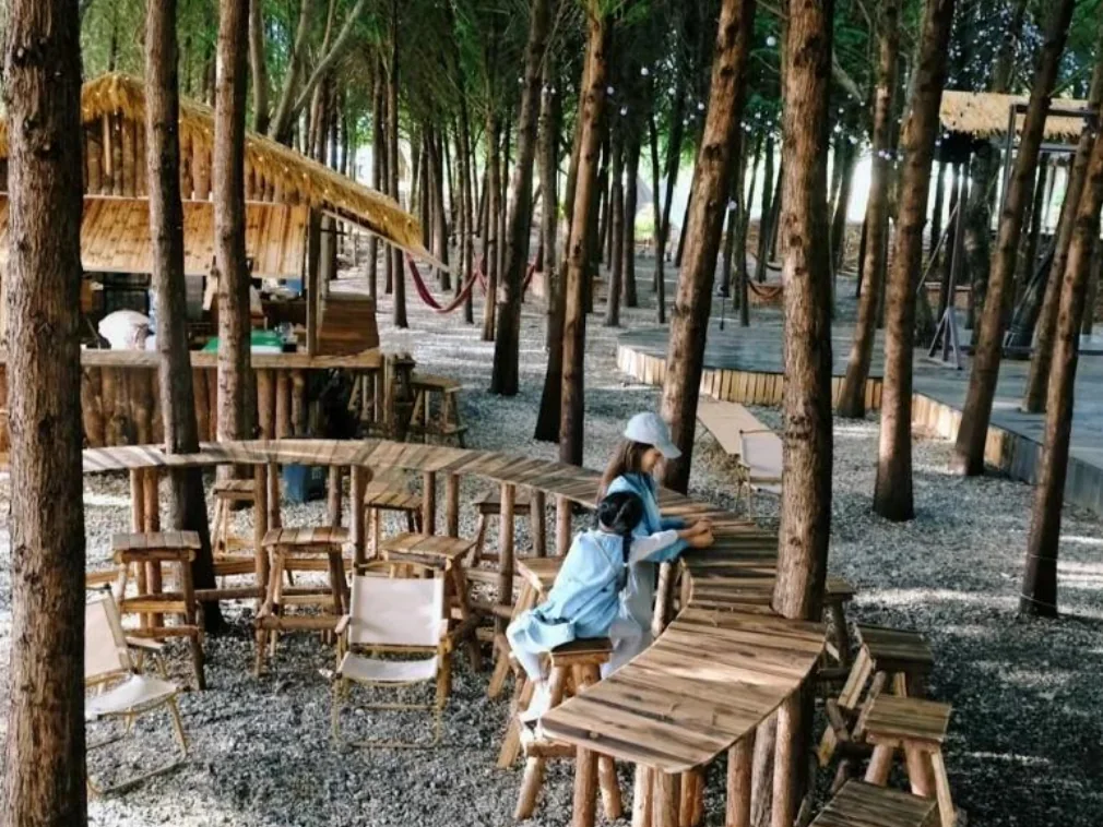 Woodland hospitality node with shared seating, a platform and human scale
