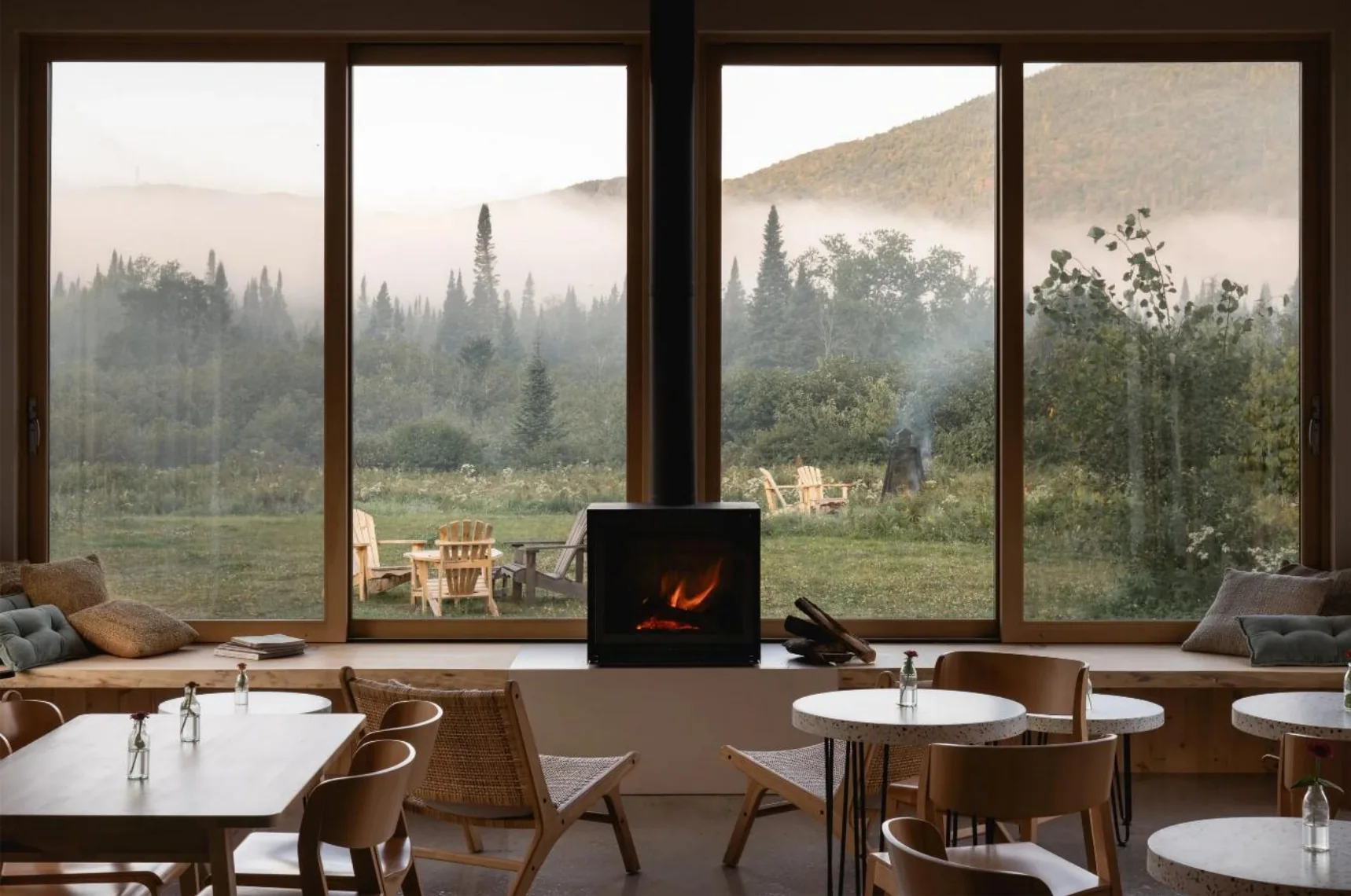 Shared cafe space with tables, a fireplace and views into the surrounding landscape